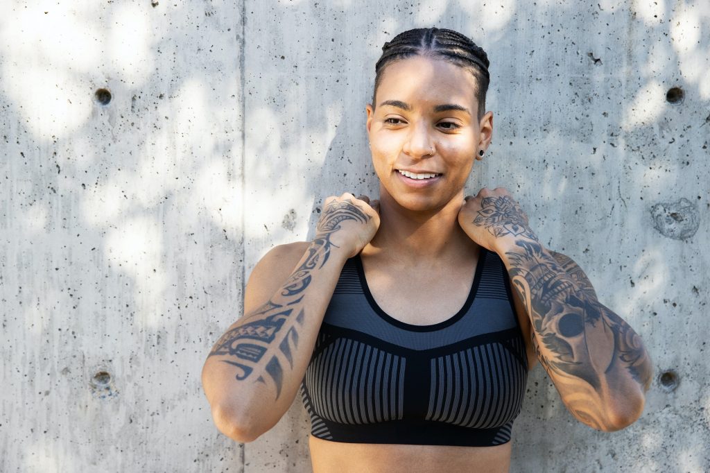 Strong, athletic African American woman with tattoos wearing athletic clothes to work out